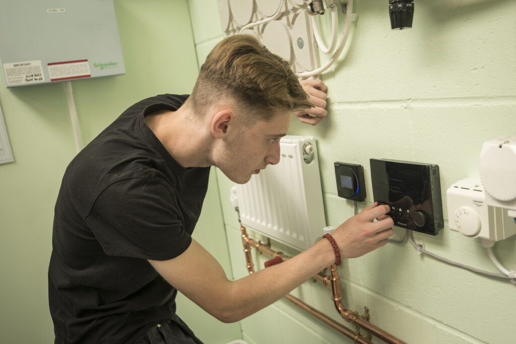 A trainee learns how to set a smart thermostat unit